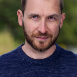 A persons headshot with them in the centre towards camera