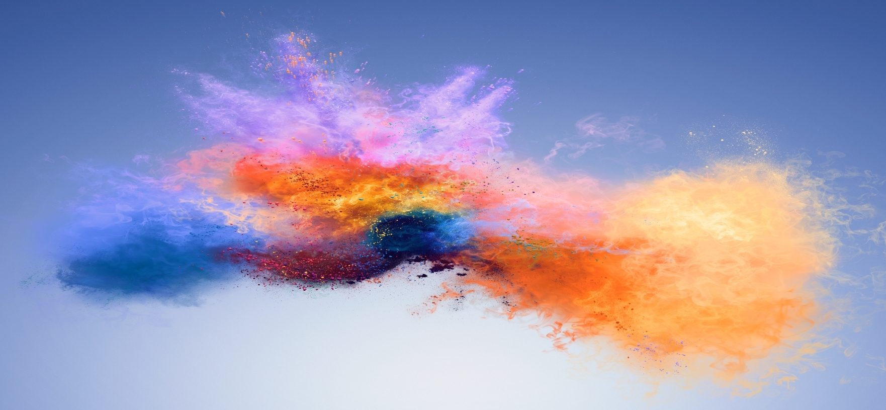 An explosion of colours, yellow, orange, red, purple, blue. All looking like dust particles on a light blue background