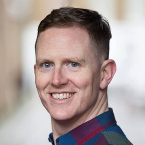 Headshot of Ben Stock - he is smiling, has short brown hair and is wearing a checked shirt.