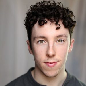 Headshot of white man with dark curly hair