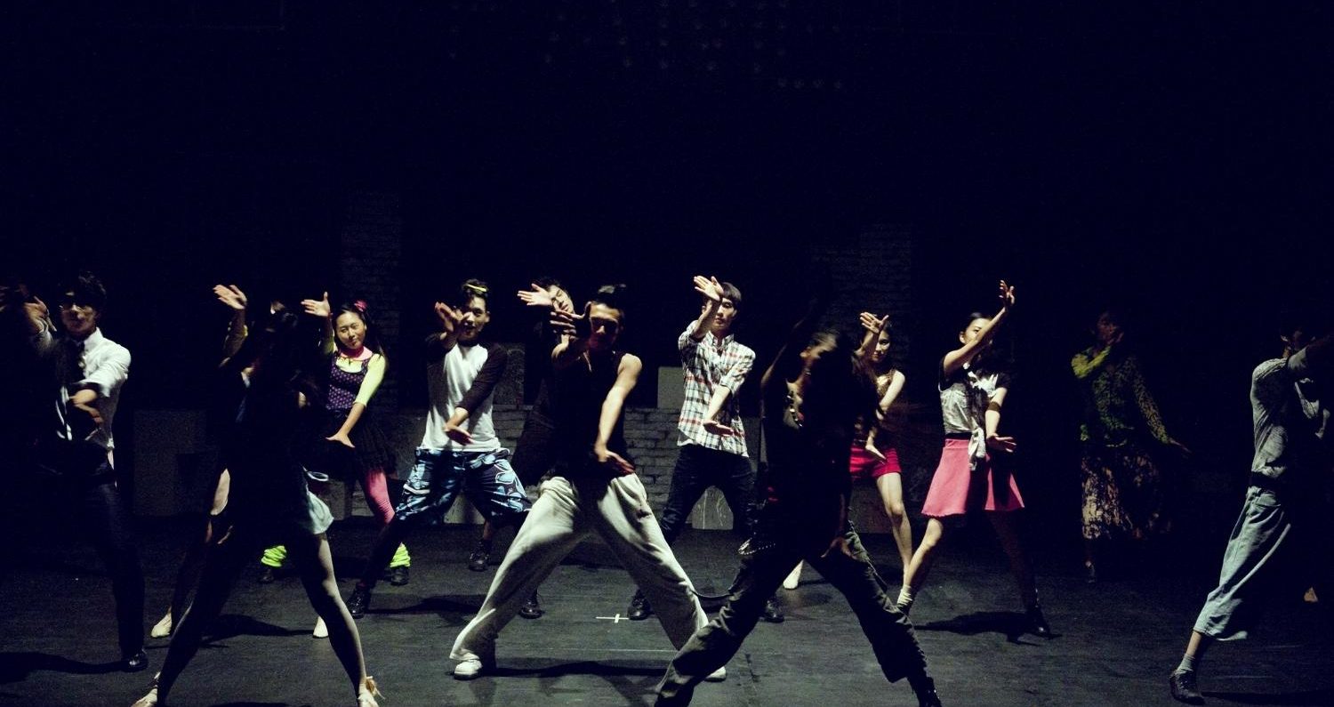A group of young people dancing in dim light.