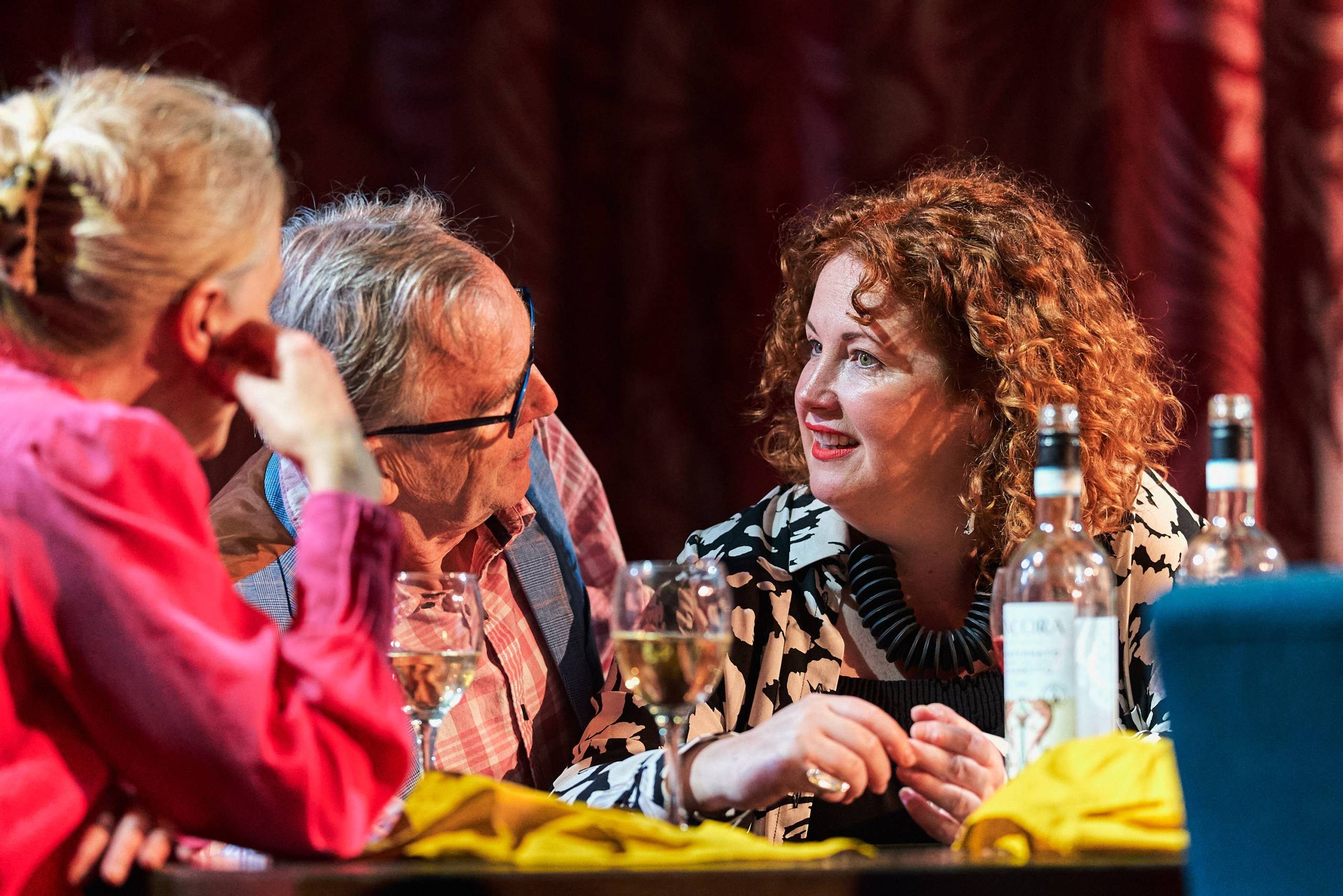 Two women and a man leaning into one another having a discussion.