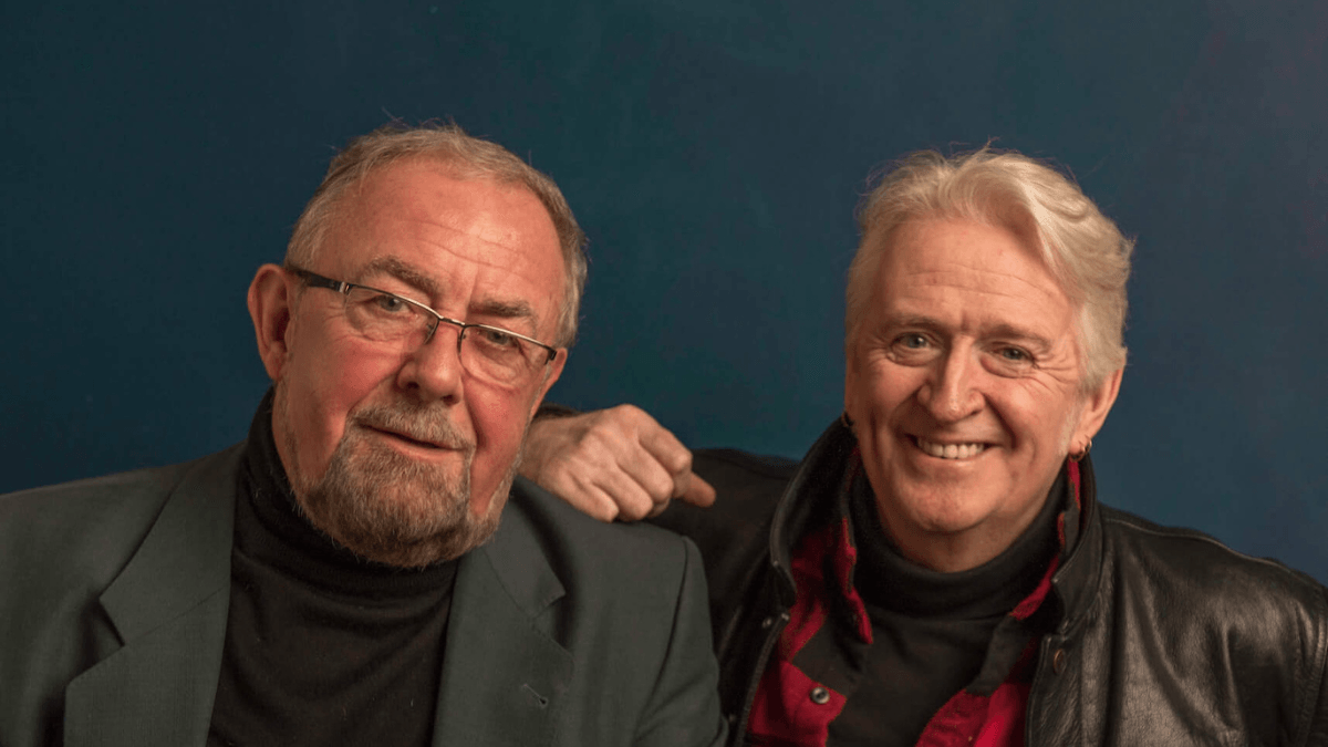 Two smiling men sitting side by side.