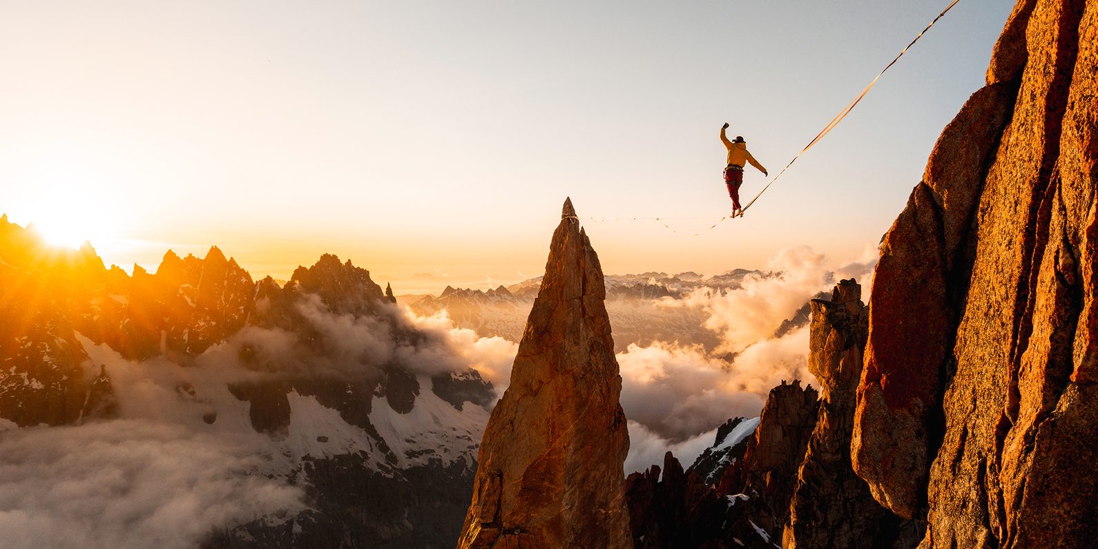 Person on high wire in mountain landscape.