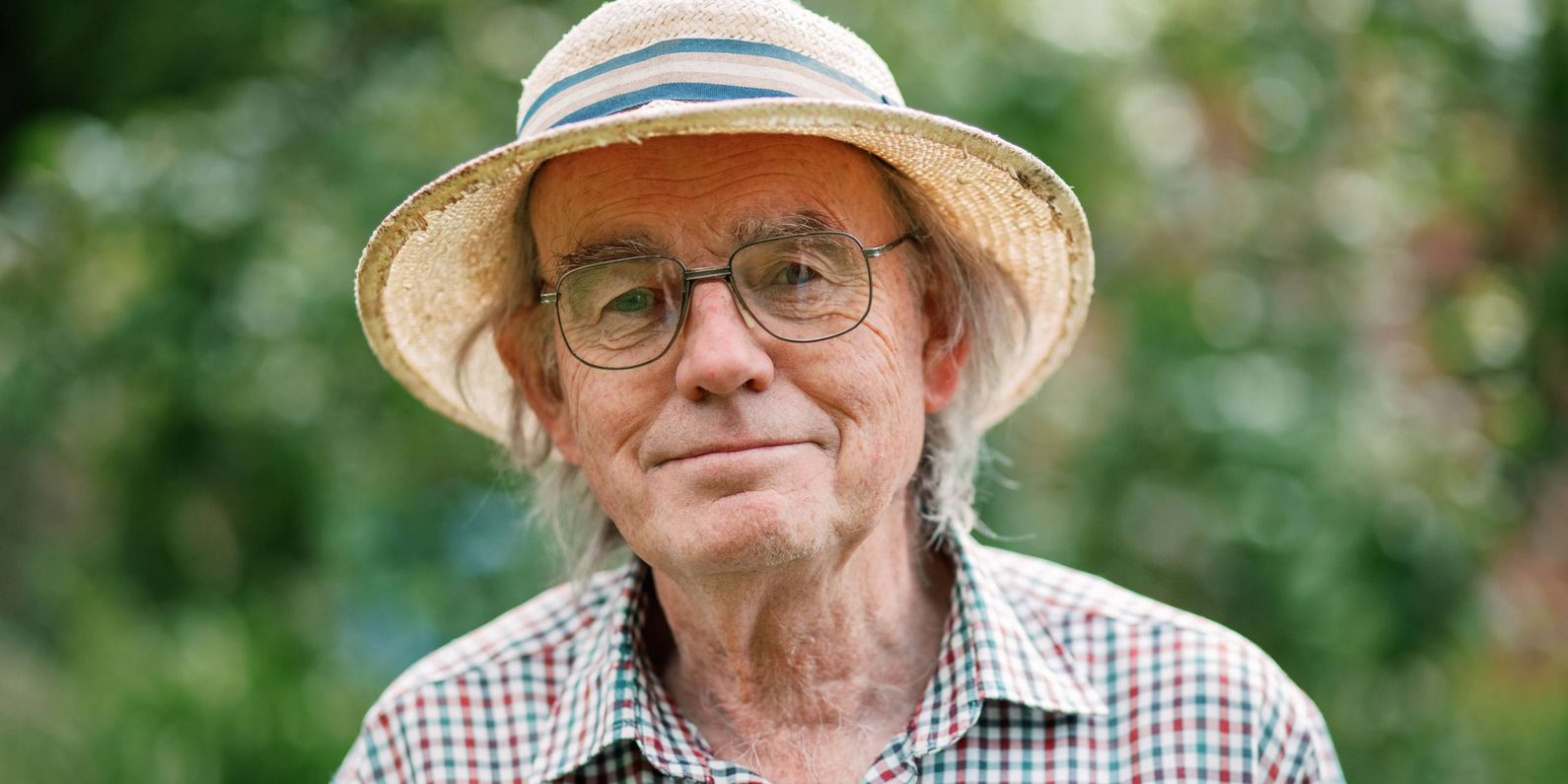 A man in a hat, glasses and checked shirt.