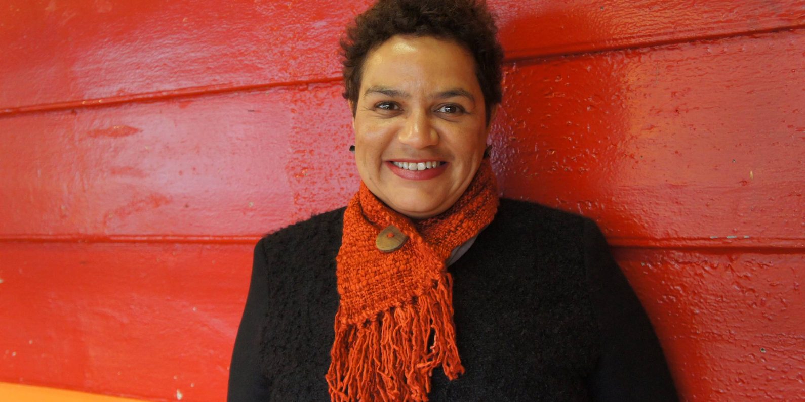 A woman with a red scarf with a red backdrop.