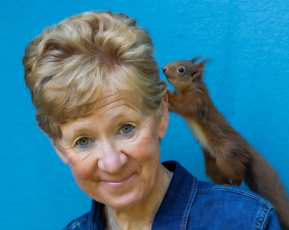 Polly Pullar. A woman wearing a blue shirt with a red squirrel on her shoulder.
