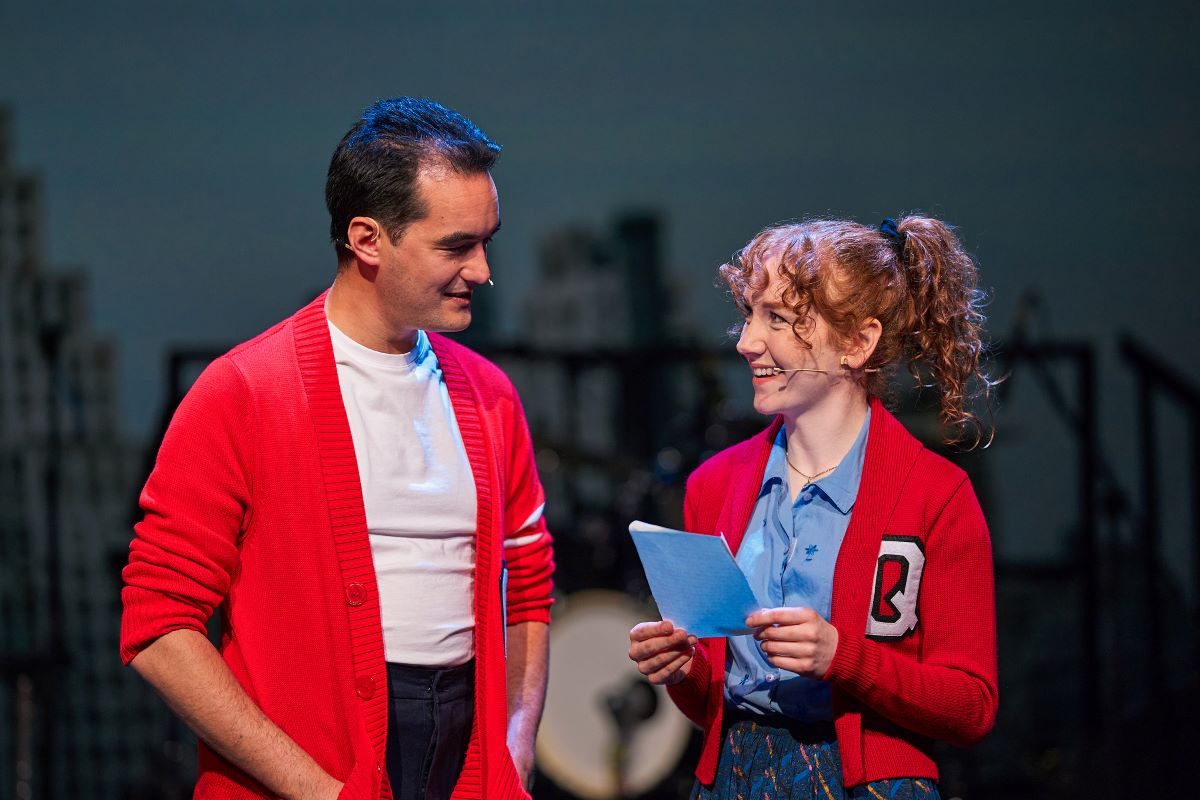 Two actors in costume smiling at each other.