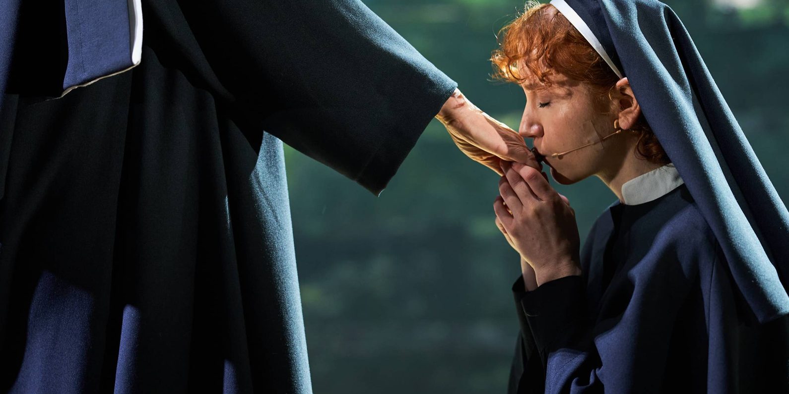 An actor dressed in nun costume kissing another nun's hand