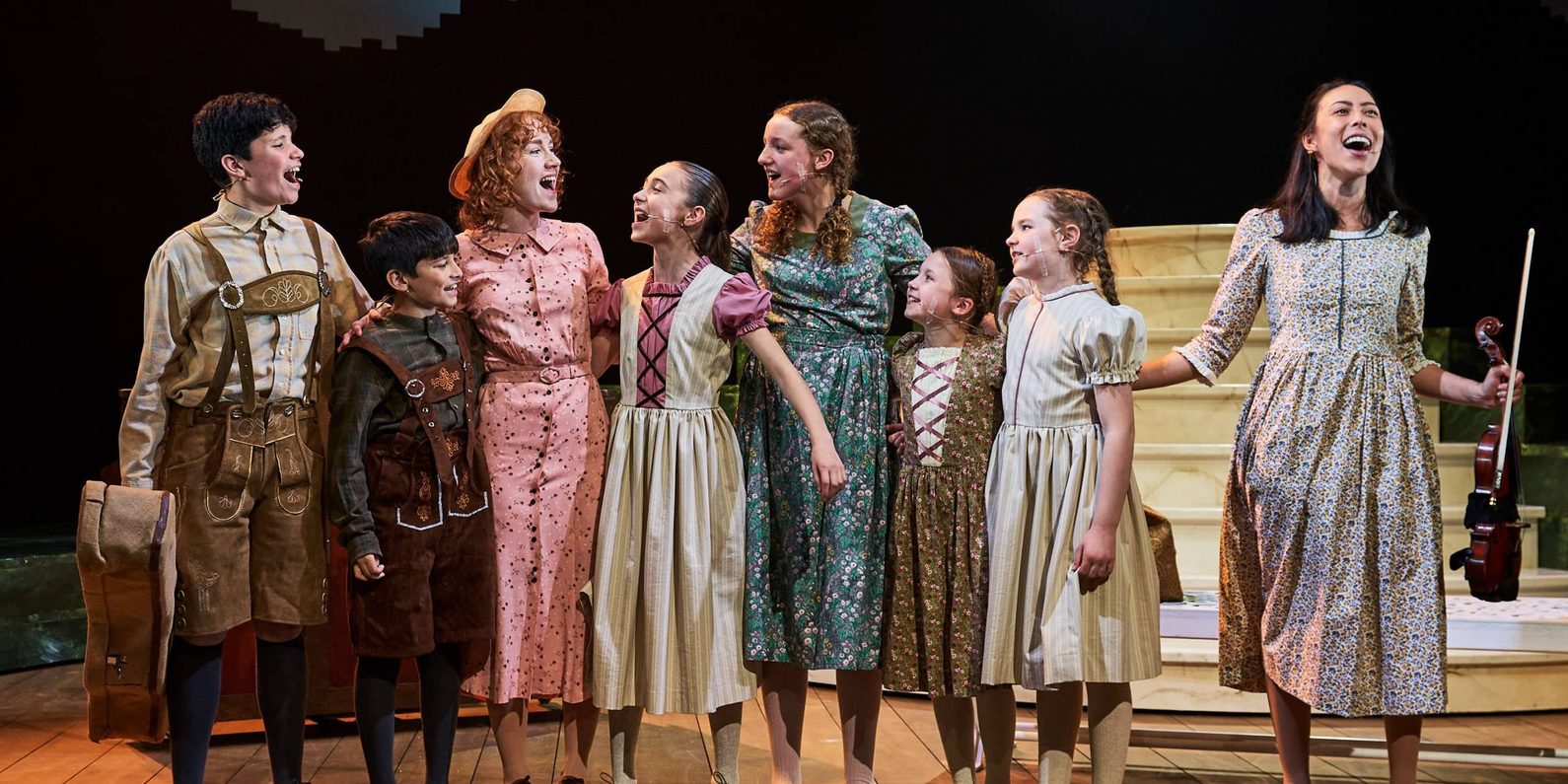 A group of actors including some children in costume, singing