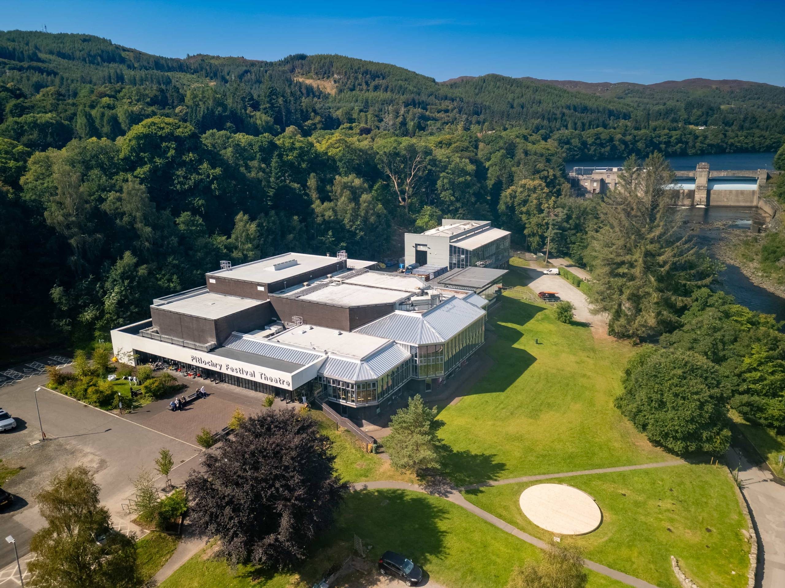 Aerial view of a theatre building in a woodland and grassy location